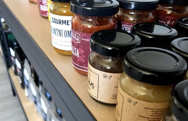 Různé druhy koření a omáček od Delight CoffSpice, prezentované na skleněných policích